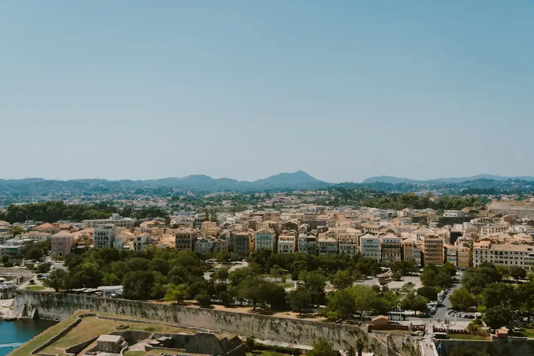 A high-angle aerial view of the historic red-roofed buildings and narrow streets in Corfu Old Town, Greece.