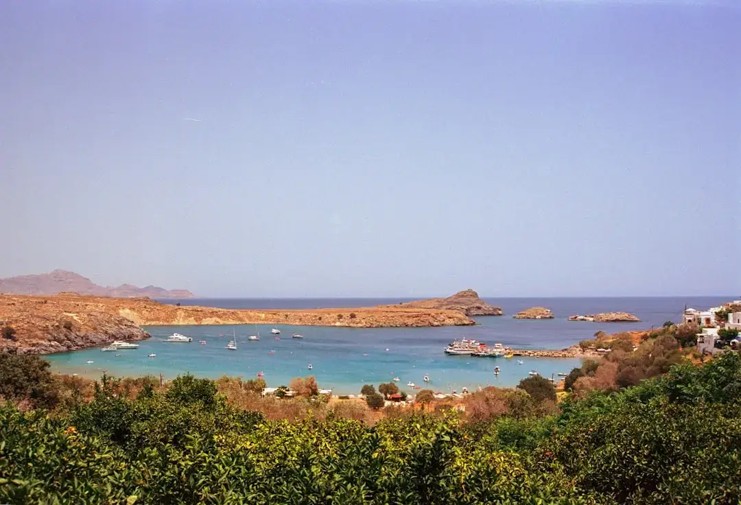 High altitude aerial view of the turquoise waters and white buildings of Lindos Bay in Rhodes, Greece.