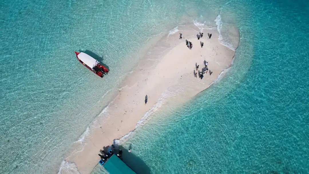 A breathtaking aerial perspective of the long white sandbar connecting the two islands of Nosy Iranja, surrounded by turquoise ocean water.