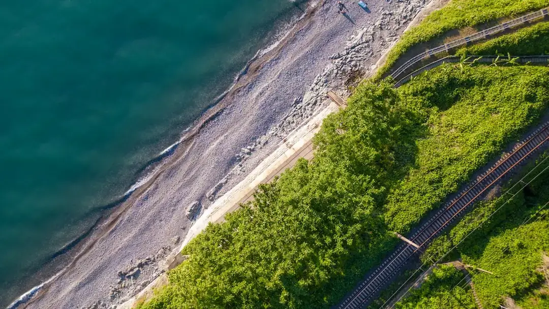 A breathtaking aerial view of a winding coastline where turquoise ocean waves meet a lush tropical shore.