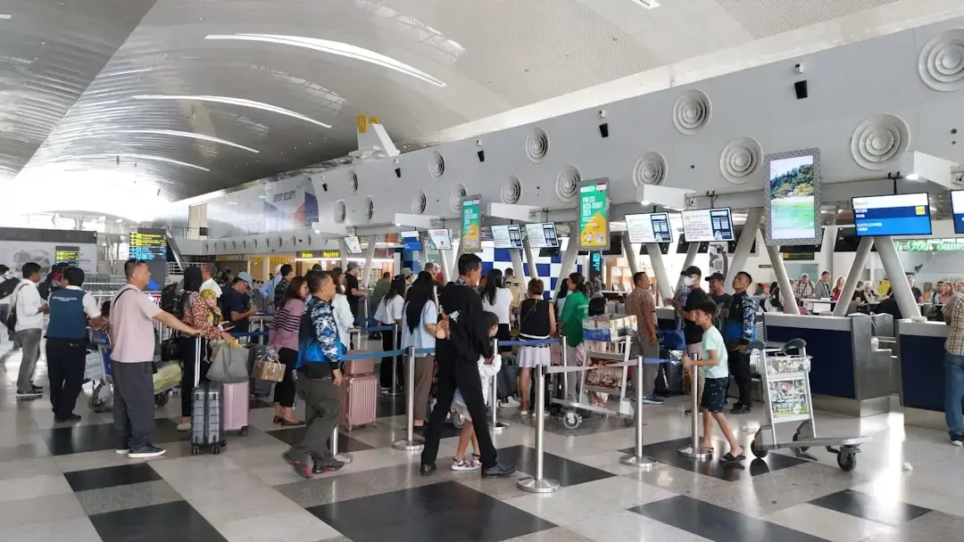 A brightly lit luxury duty free shopping area inside a modern international airport terminal with travelers browsing retail products.