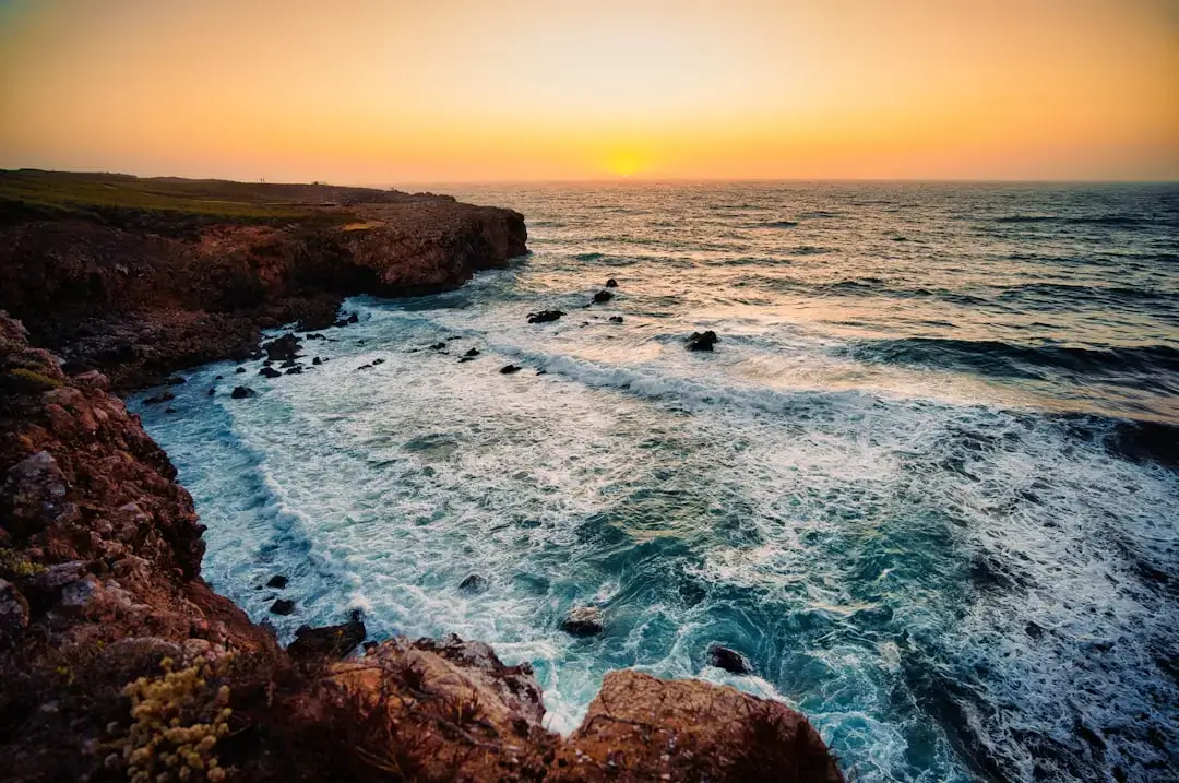 Dramatic golden sandstone cliffs overlooking a turquoise ocean beach in the Algarve region of Portugal.
