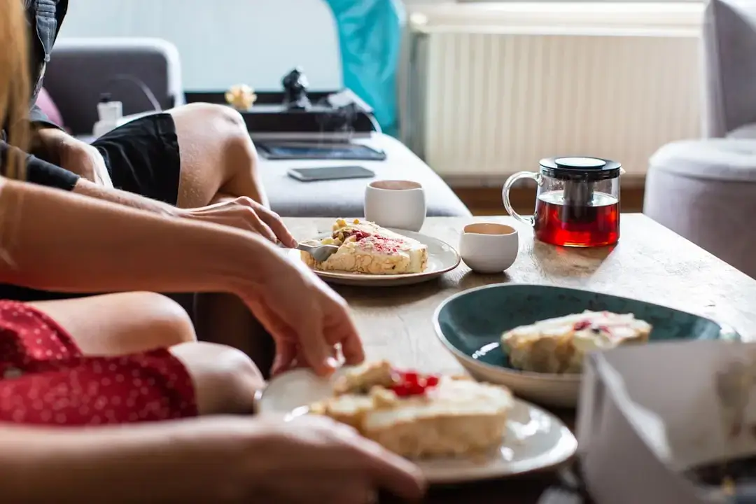 A steaming cup of coffee with pouring milk next to a warm stack of pancakes on a breakfast table.