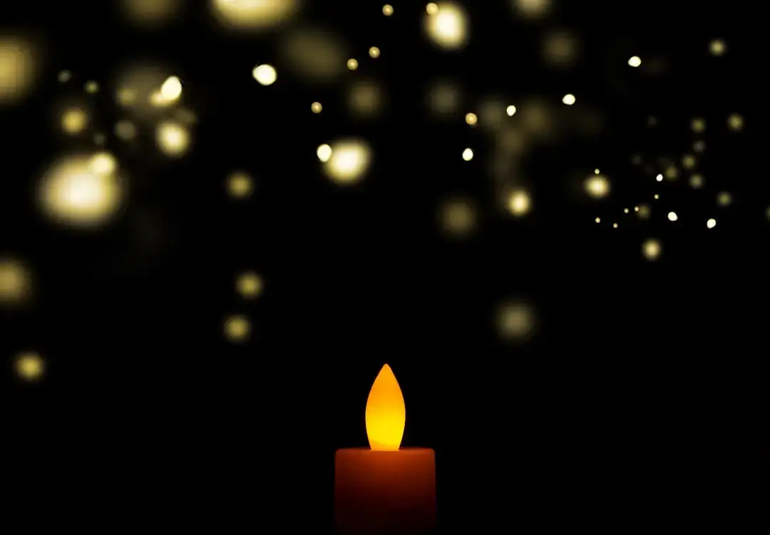A warm and gentle candle flame flickering softly in a dark, cozy room.