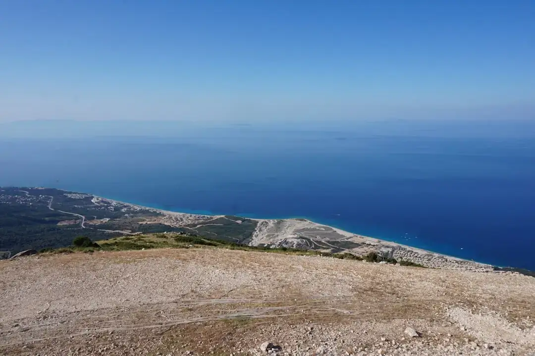 Aerial view of crystal clear turquoise water washing against the rocky shore of the Albanian Riviera.