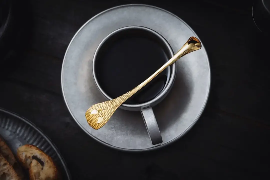 Close-up of thick golden honey dripping slowly from a wooden honey dipper spoon