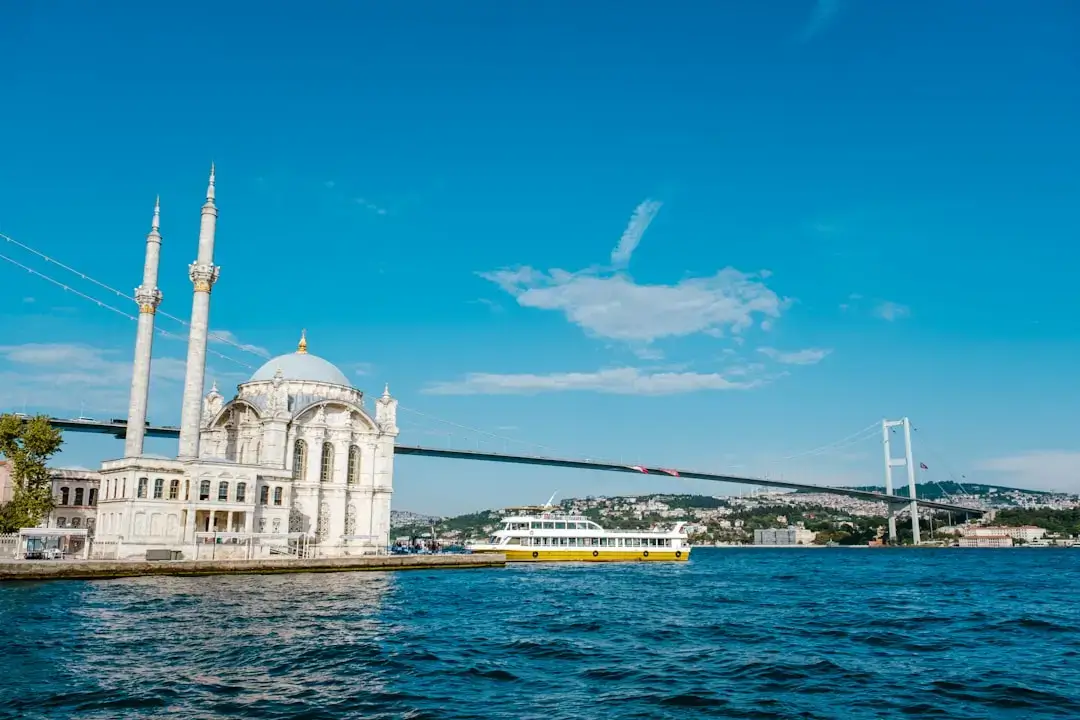 A panoramic view of the 15 July Martyrs Bridge crossing the Bosphorus in Istanbul during a vibrant orange and pink sunset.