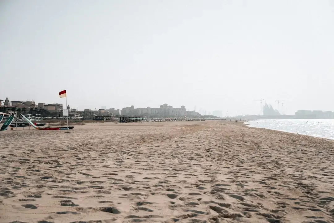 A kitesurfer riding the waves along the sunny Dubai coastline with the city skyline in the background.