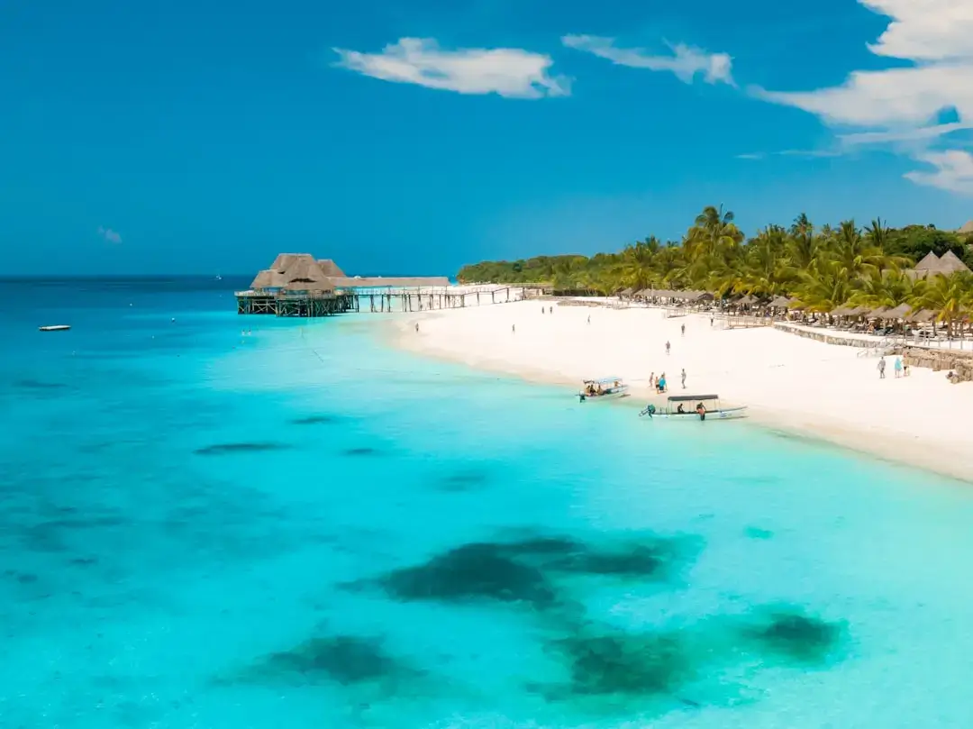 A crystal clear infinity swimming pool at a luxury luxury resort in Zanzibar overlooking the turquoise ocean at sunset