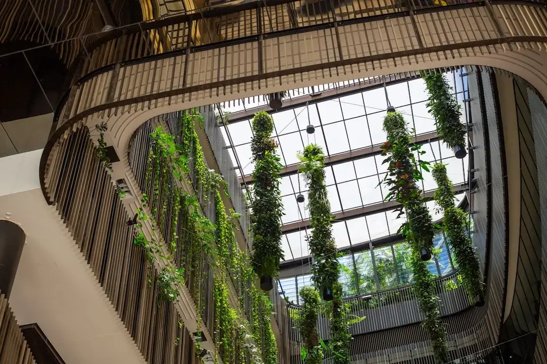 Bright and modern sustainable office workspace featuring biophilic design with abundant indoor plants, natural wood desk, and natural light.