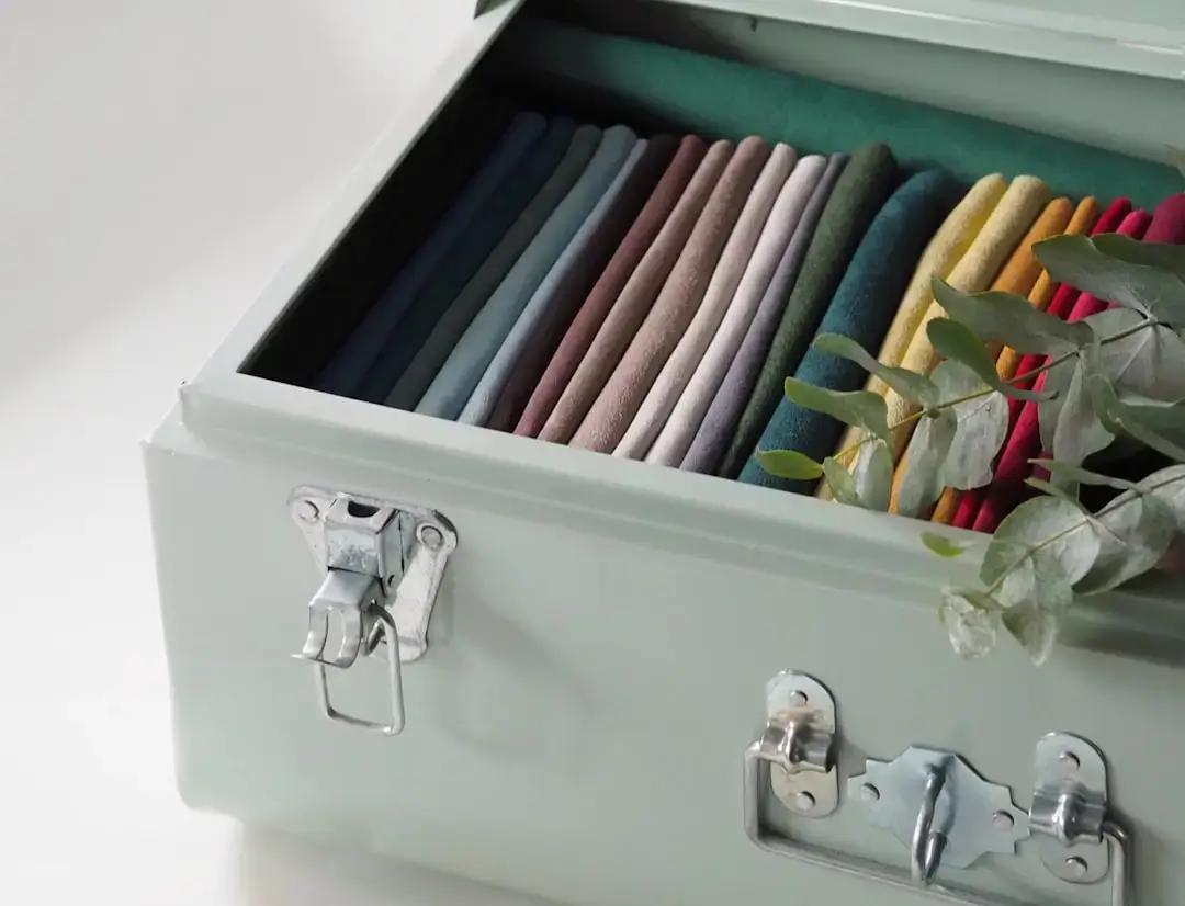 An overhead view of a neatly packed travel suitcase with folded clothes, shoes, and travel accessories.