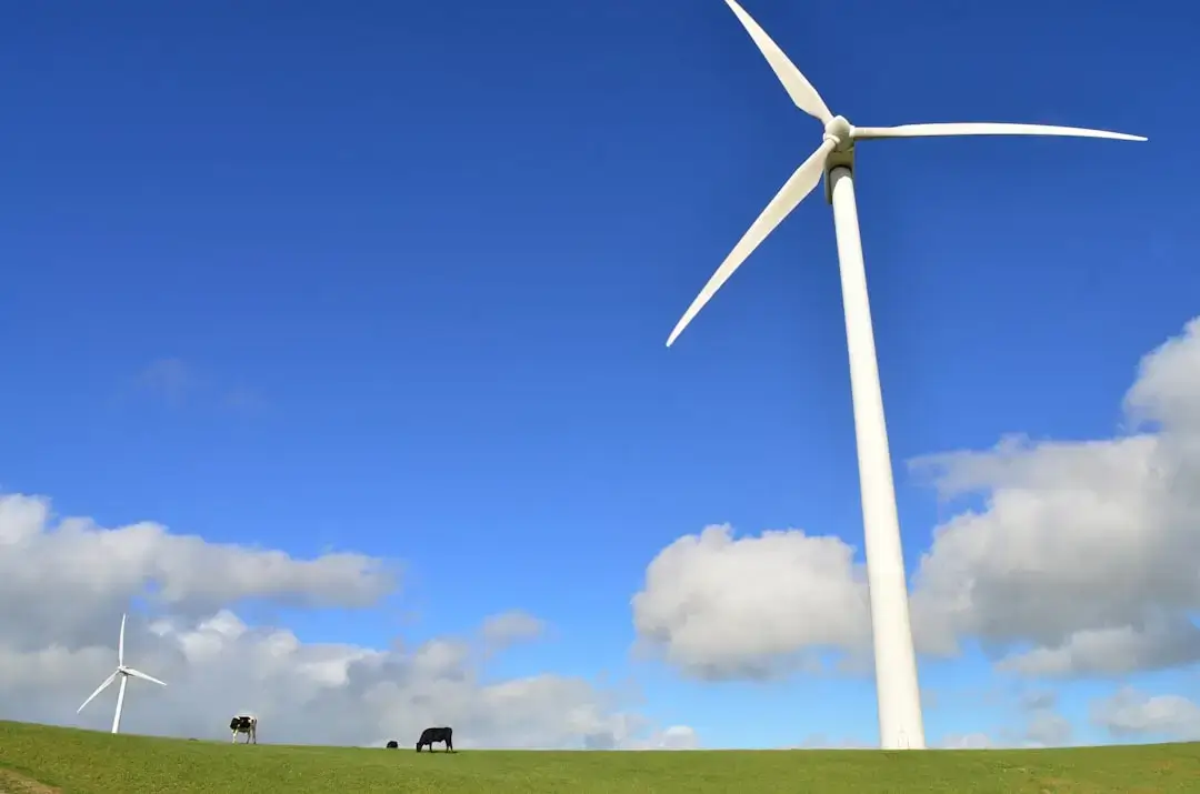 Wind turbines and solar panels in a lush green field under a clear blue sky representing clean renewable energy.