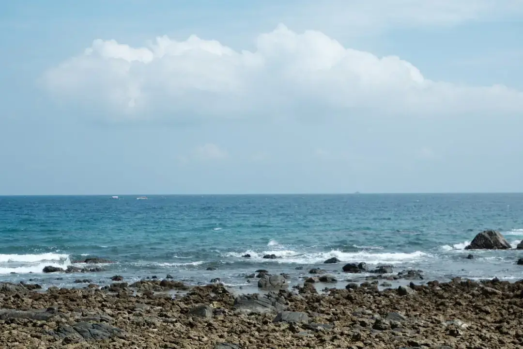 A panoramic view of a sunny beach in Rhodes with clear blue water and safety flags on the shore.