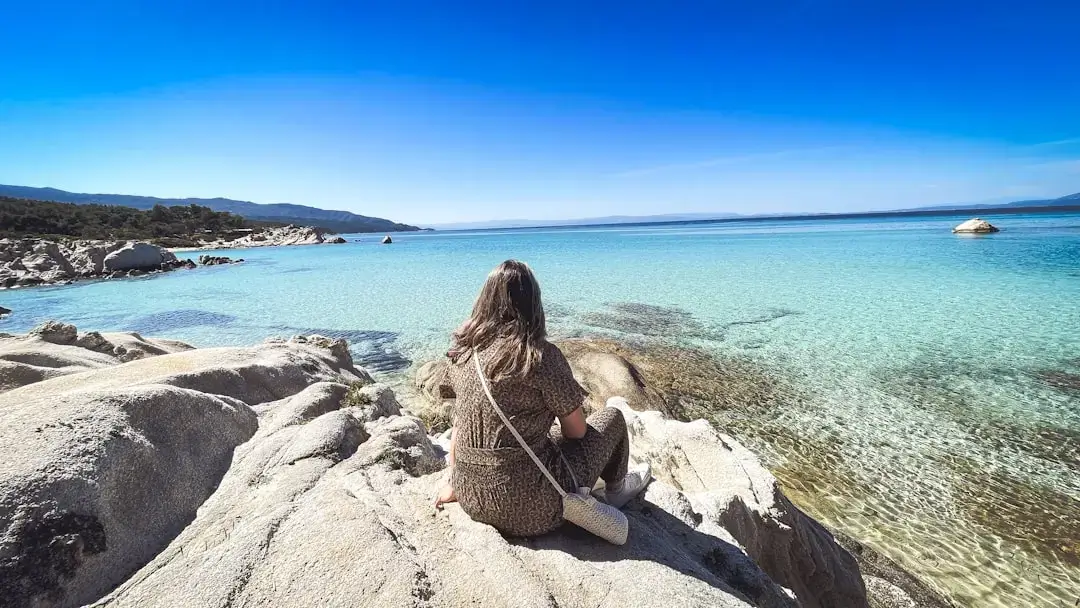 A person snorkeling in the vibrant turquoise crystal clear waters of the Greek coast.