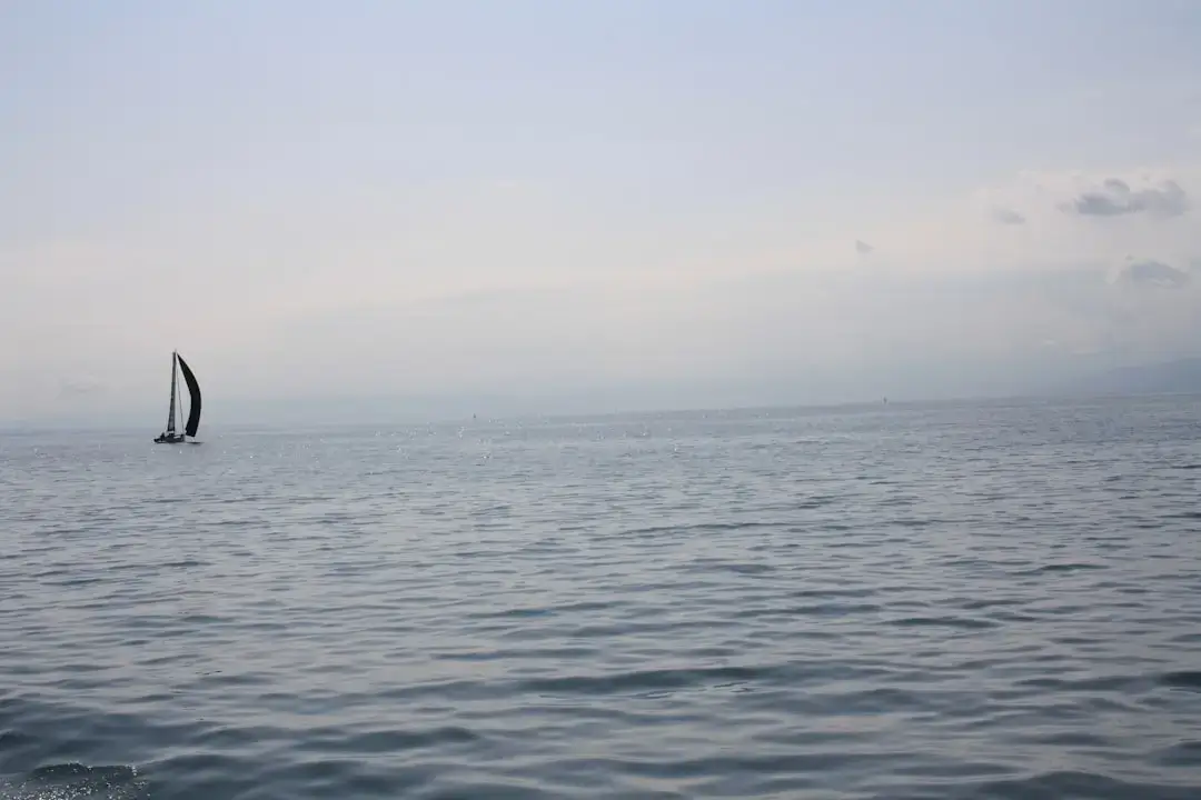 A young teenager expertly navigating a small sailboat on a calm scenic lake in Poland during sunset.