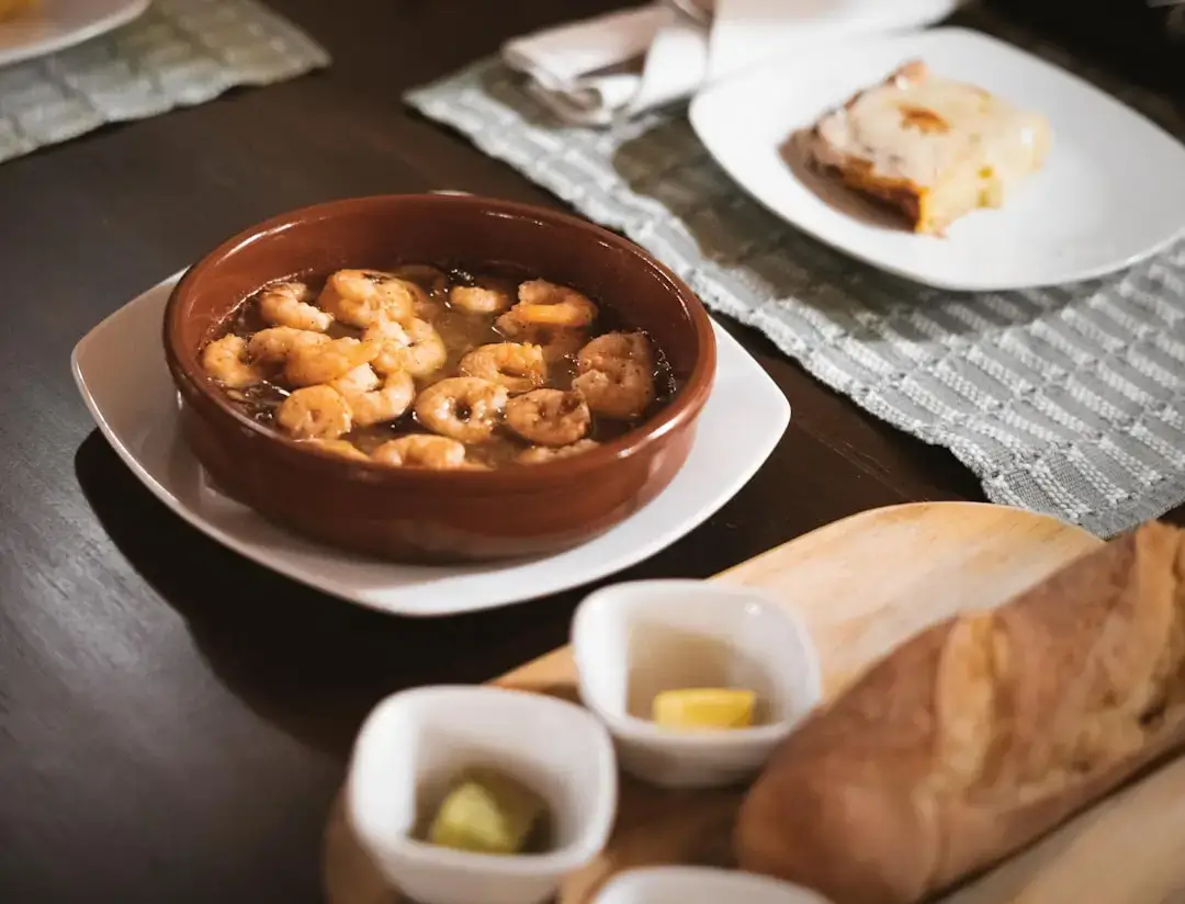 A variety of authentic Spanish tapas dishes served on small plates on a rustic wooden restaurant table.