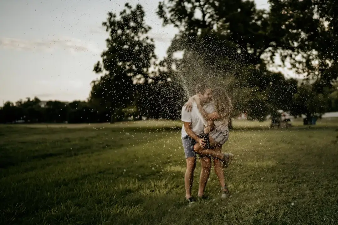 An automatic garden sprinkler spraying water over a lush green grass lawn during a sunny day