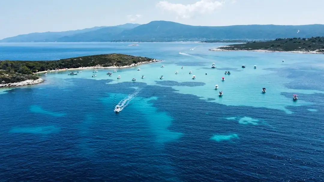 A large white passenger ferry boat sailing across the deep blue Aegean Sea in Greece under a bright sunny sky.