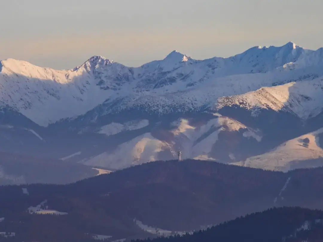 A breathtaking panoramic view of the snow-covered Polish Tatra Mountains under a clear winter sky.