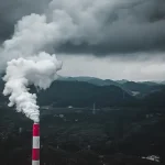a smokestack emits from a pipe on a cloudy day