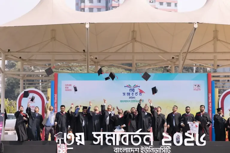 Graduates in caps and gowns toss hats in the air.