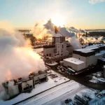 Industrial factory emitting steam on a snowy day