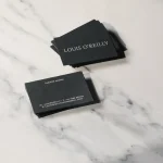 A pair of business cards sitting on top of a marble counter
