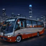 Bus driving on a road at night with city lights.