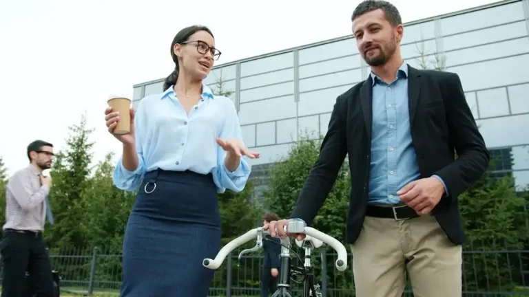 Two business professionals discuss near a bicycle.