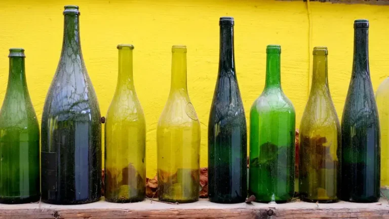 A close-up of empty green glass bottles sitting outdoors, representing recycling and waste management.