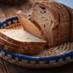 A fresh loaf of sliced bread on a wooden surface representing food waste management and recycling