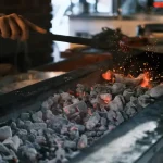 A person safely cleaning black soot and ash from a fireplace for proper waste disposal.