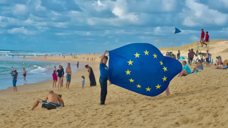 The European Union flag waving in front of a clear blue sky, illustrating international relations.