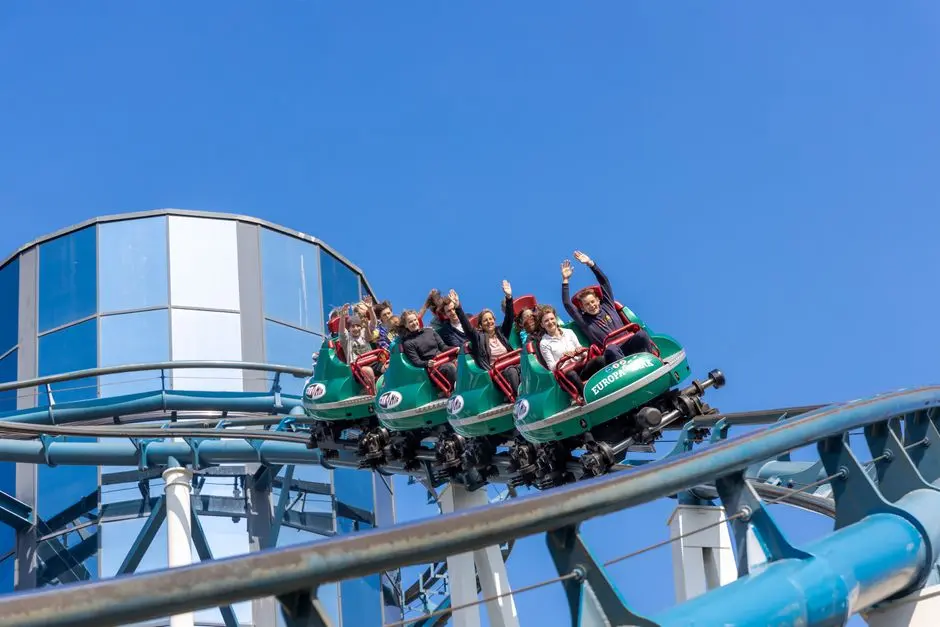 Ludzie cieszący się ekscytującą przejażdżką kolejką górską w Europa-Park pod czystym niebieskim niebem.